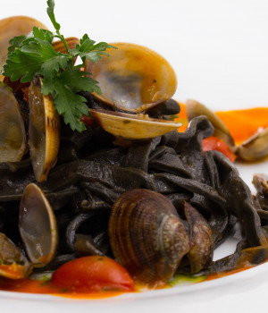 Squid ink fettuccine with clams and datterini tomatoes sauce